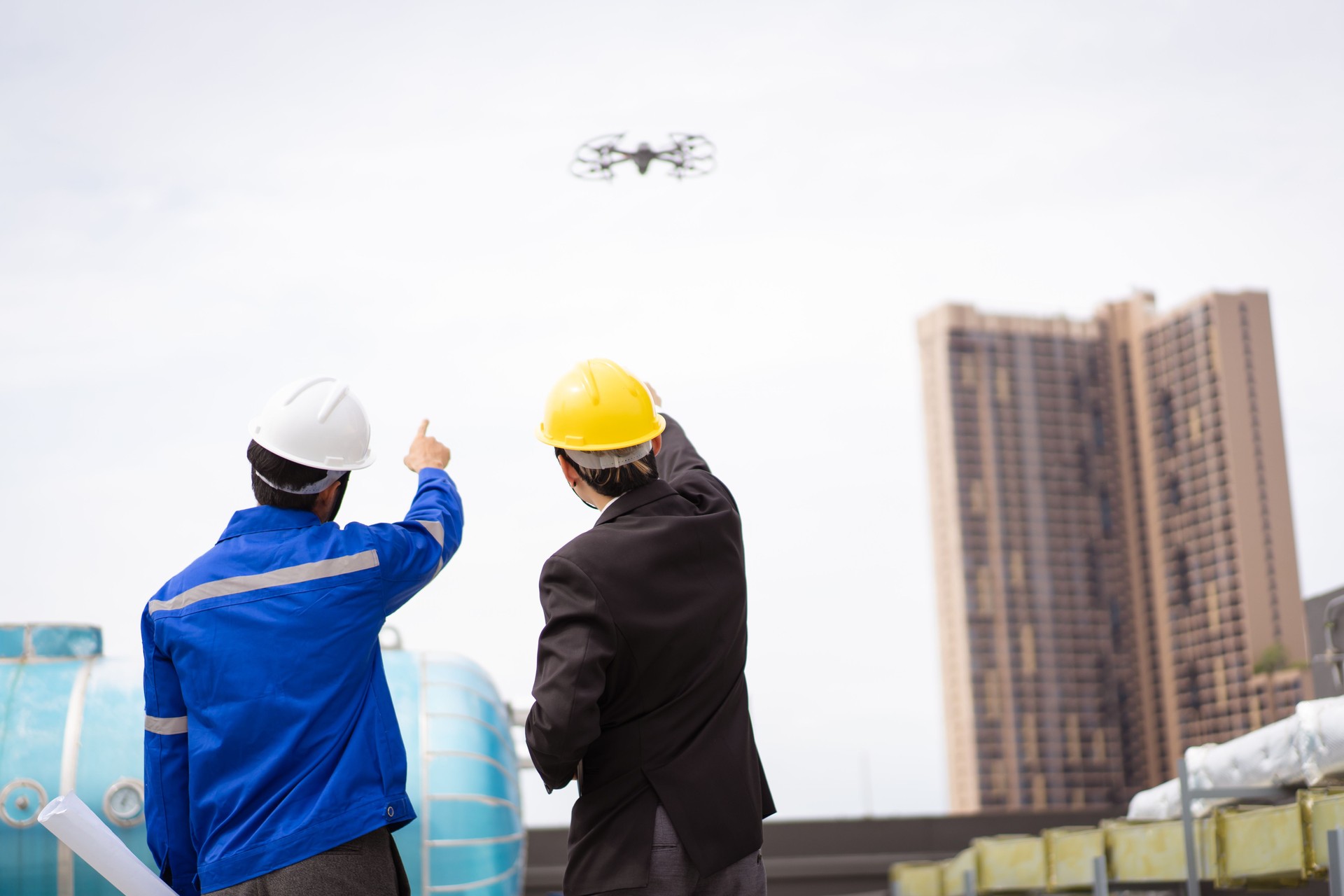 Engineer - contractor flying a UAV or drone over the building.
