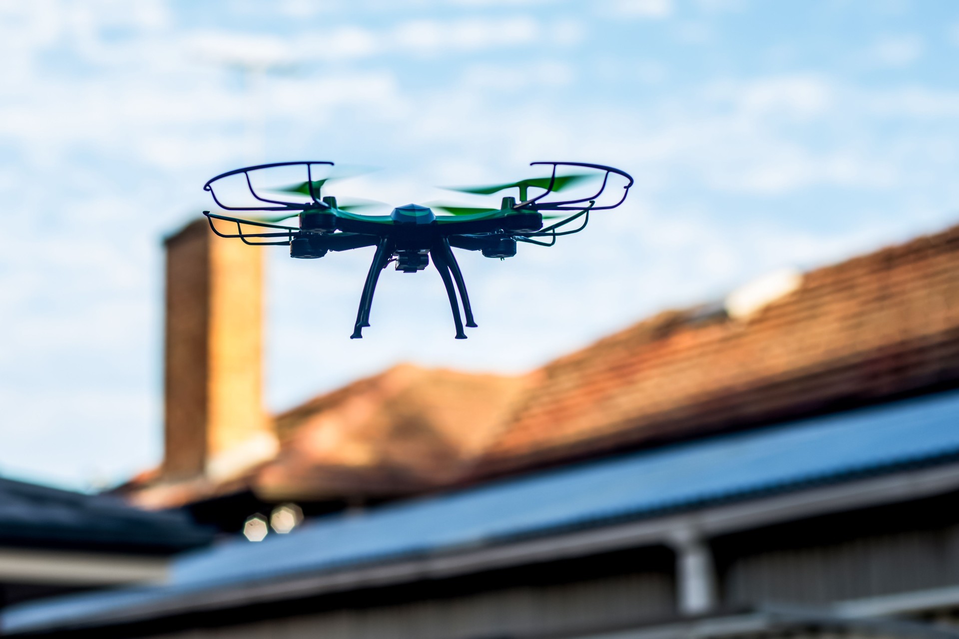A drone flying above a building, capturing roof inspections and aerial footage for assessment and maintenance purposes.